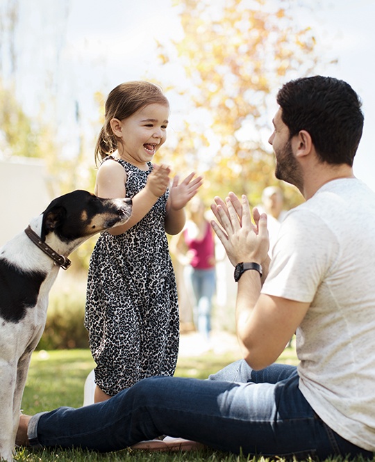Dad with daughter and dog on the lawn