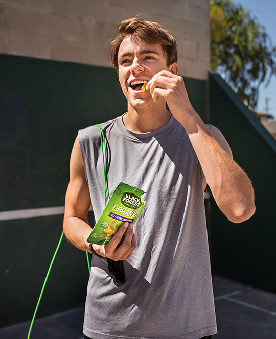 Guy eating gummy worms after jump roping at park